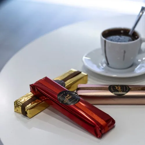 Tazzina di caffè accanto a tavolette di cioccolato artigianale